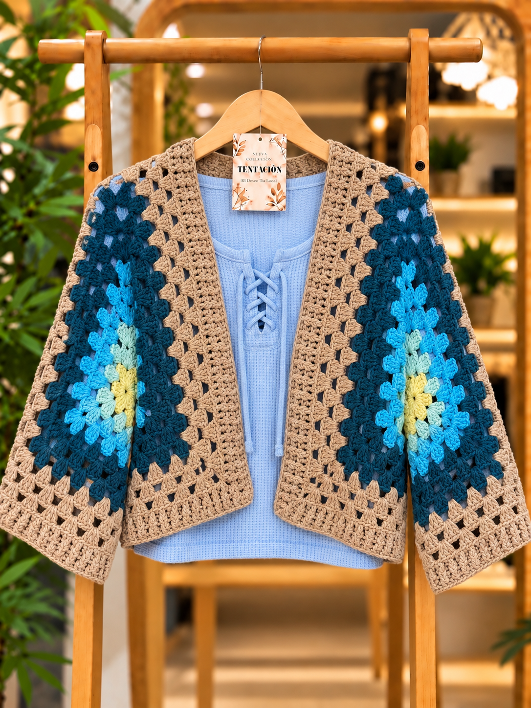 Saco Crochet Corto Berrie de frente abierto, con motivos en azules, verde y amarillo y bordes beige, mostrado sobre una musculosa celeste.