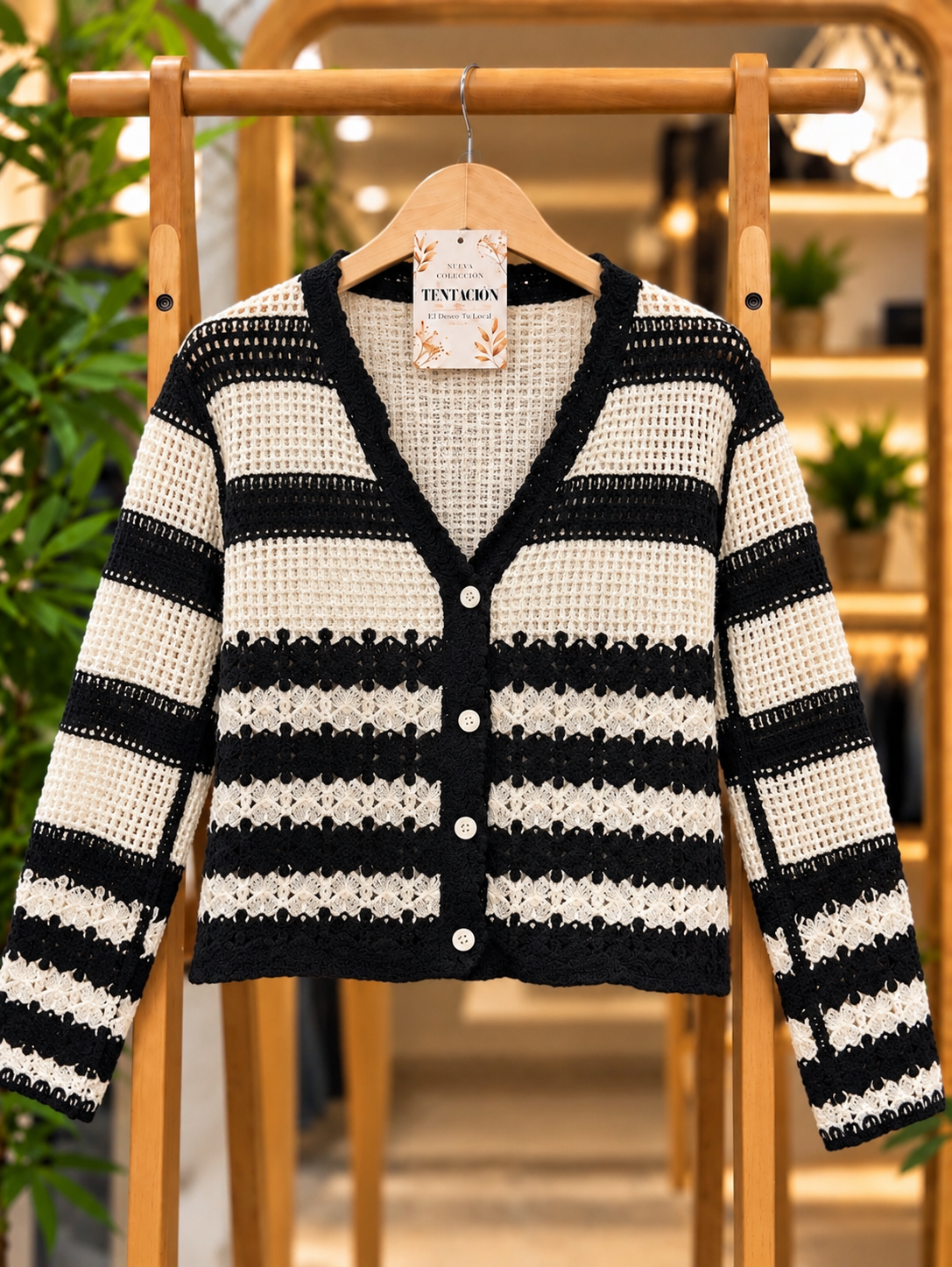 Saco de Hilo Cecilia Negro en percha, con rayas negras y crudas, tejido calado, escote en V y cuatro botones claros.